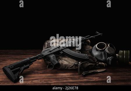Carbina sovietica in kit corpo moderno. Armi della Russia e dell'Unione Sovietica. Classico fucile d'assalto AK sovietico e maschera a gas su sfondo di legno. Foto Stock