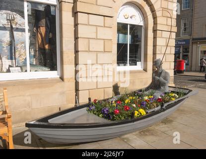 Una scultura di una persona che pesca all'interno di una barca a remi all'esterno del River Tweed Museum of Salmon Fishing nel municipio di Kelso, Scottish Borders, Scozia. Foto Stock