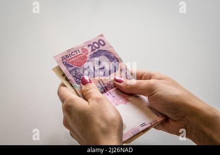 Le mani della donna con unghie dipinte contando le banconote di Hryvnia ucraine su sfondo bianco (concetto economico) Foto Stock