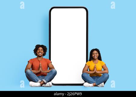 Coppia nera rilassata seduta da smartphone enorme con schermo vuoto Foto Stock