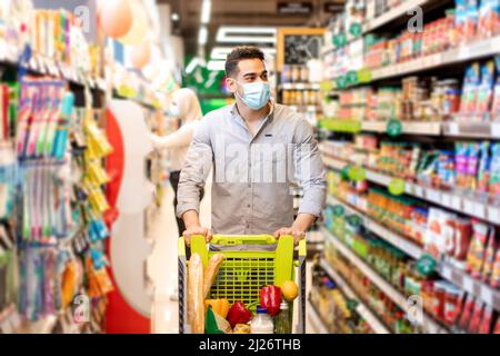 Middle Eastern Man Shopping indossare maschera acquistare cibo in supermercato Foto Stock