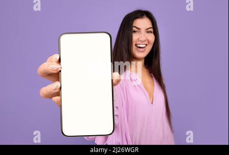 Bella giovane donna che dimostra grande bianco smartphone in mano Foto Stock