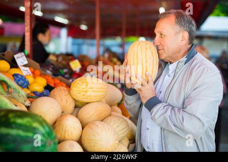 Uomo di mezza età che acquista melone Foto Stock