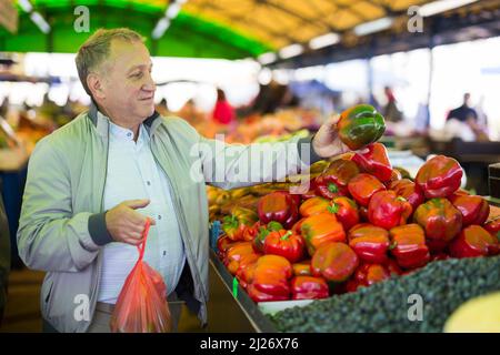 Uomo che acquista peperoni in gregrocery Foto Stock