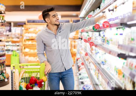 Uomo Arabo che prende la bottiglia di latte Shopping generi alimentari in supermercato Foto Stock