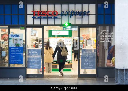 La gente lascia ed entra in un negozio Tesco nel centro di Londra dopo che è entrato in vigore il rilassamento delle regole del piano B di Covid-19. Foto Stock