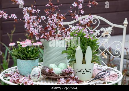 decorazione pasquale con uova di pasqua, fiori rosa di primavera e bouquet di ciliegia giapponese Foto Stock