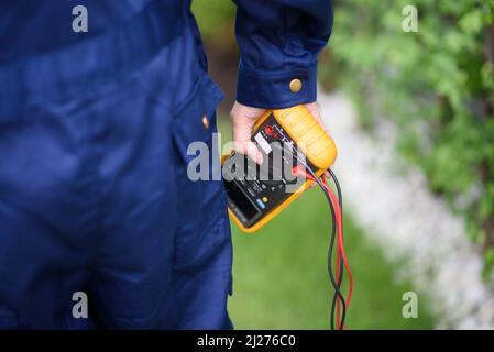 Primo piano dell'elettricista che tiene un multimetro. Foto Stock