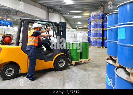 Gruppo di lavoratori nell'industria logistica lavorare in un magazzino con prodotti chimici - Sollevamento del carrello Foto Stock