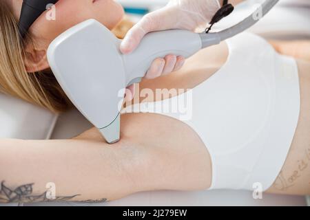 Estetista che rimuove i capelli da donna ascella con dispositivo laser Foto Stock