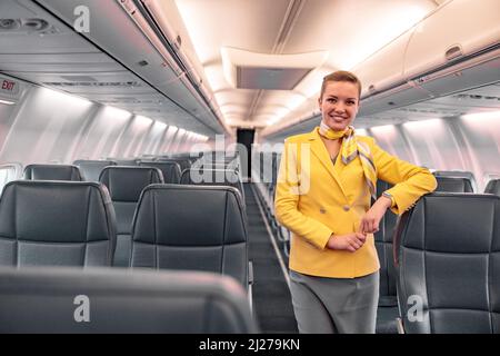Allegra stewardess in piedi nel salone passeggeri dell'aereo Foto Stock