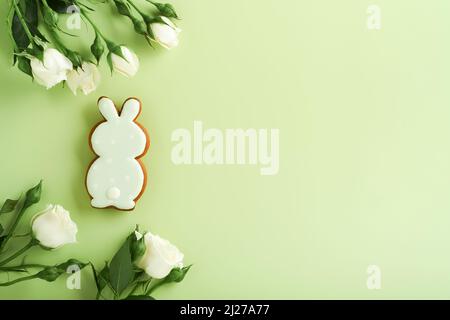 Buona Pasqua. Cartolina con biscotti di Pasqua o pan di zenzero e bellissimi fiori su sfondo verde chiaro. Vista dall'alto con spazio per i messaggi di saluto. Foto Stock