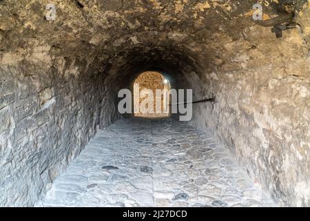 Ingresso ad una prigione fortezza costruita con pietre e con una porta boscosa Foto Stock