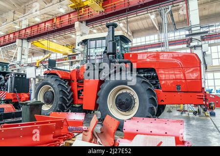 La vendemmiatrice o il trattore rosso di grandi dimensioni sono in fase di assemblaggio in fabbrica per la produzione di macchinari agricoli. Foto Stock
