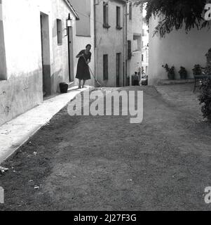 1950s, storica, Italia, una signora che si snodava su un sentiero di ghiaia fuori dalla casa del suo villaggio. Foto Stock