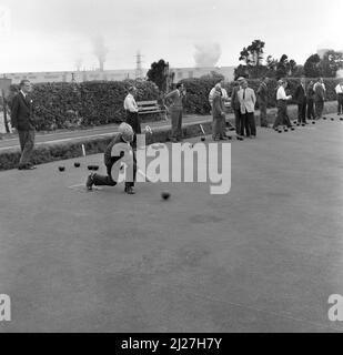 1950s, historcal, gli uomini che giocano le bocce verdi della corona al randello di bowling della pianta di acciaio a Abbey Works, Galles, Regno Unito, il nome della compagnia di acciaio del Galles limitato ed i camini delle sue fabbriche possono essere visti in lontananza. Foto Stock