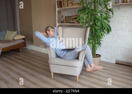 stanco di lavorare su un computer portatile, un uomo è seduto su una sedia appoggiata indietro. Foto Stock