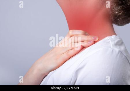 Donna che soffre di mal di gola. Mano che tocca il collo con punto rosso primo piano. Assistenza sanitaria, concetto di malattia. Influenza, raffreddore, infiammazione. Foto di alta qualità Foto Stock