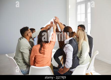 Diverse persone si uniscono alle mani impegnate nella formazione di squadra Foto Stock