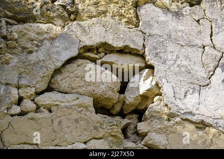 Vecchio muro in pietra dilapidato con resti di gesso. Antiche rovine. Primo piano. Messa a fuoco selettiva. Foto Stock
