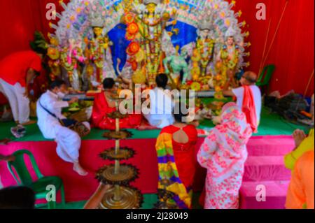 Immagine sfocata della Dea Durga è adorata dai sacerdoti indù durante sondhipujo aarti. Durga puja durante la pandemia di Covid 19. Foto Stock