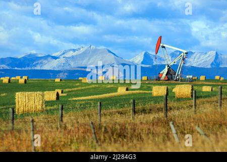 Un carro di perforazione per pickjack dell'industria petrolifera e del gas nelle praterie canadesi con le Montagne Rocciose canadesi ad Alberta, Canada. Foto Stock