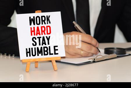 Citazioni di parola di LAVORO DURO SOGGIORNO UMILE su carte colorate memo con sfondo di legno Foto Stock