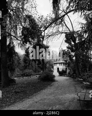 Paesaggio di un parco in bianco e nero con un sentiero, una fila di panchine e uno stand sullo sfondo. Formato quadrato. Foto Stock