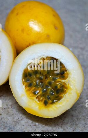 Frutta intera di passione e una metà in un fondo di granito Foto Stock