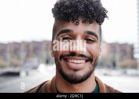 Giovane latino sorridente con la fotocamera all'aperto - Focus sul volto Foto Stock