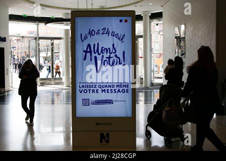 Nizza, Francia. 29th Mar 2022. Gli amanti dello shopping passano davanti a un annuncio digitale sulle elezioni presidenziali francesi del 2022 in un centro commerciale. Il primo turno delle elezioni presidenziali francesi del 2022 si svolgerà domenica 10th aprile 2022. Credit: SOPA Images Limited/Alamy Live News Foto Stock