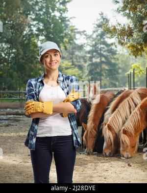 Donna stud farm lavoratore in posa con cavalli nella parte posteriore Foto Stock