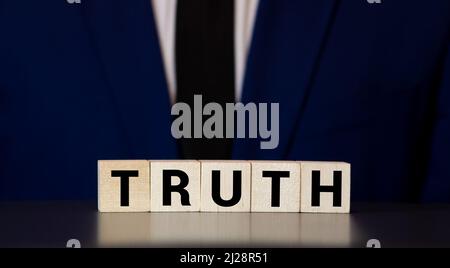 Verità - parola da blocchi di legno con lettere, fatti reali concetto di verità, lettere casuali intorno, sfondo bianco. Foto Stock
