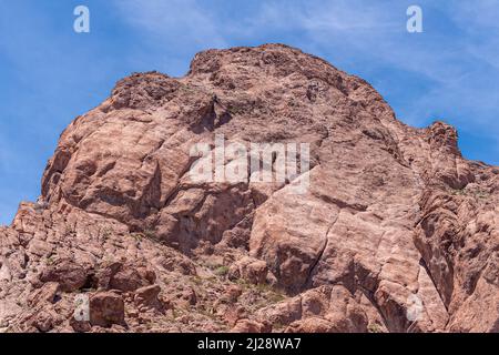 Nelson, Nevada, USA - 21 maggio 2011: Cima marrone della montagna lungo la strada 165 nel canyon di Eldorado sotto il cielo blu. Alcuni dettagli verdi di erbaccia. Foto Stock