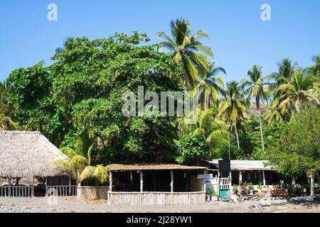 Vista nel villaggio turistico di El Tunco, El Salvador. Capanne e palme sulla riva dell'Oceano Pacifico Foto Stock