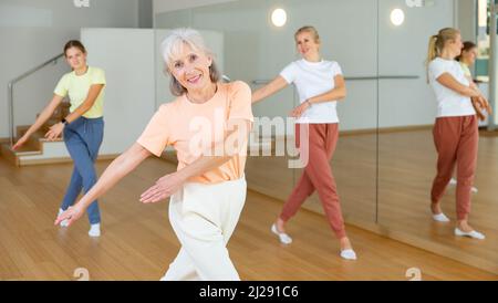 Donna anziana che impara danza aerobica con i suoi parenti più giovani Foto Stock