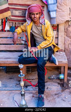 Un Ritratto di un giovane uomo che fuma Una pipa di Shisha, Petra, Giordania, Asia. Foto Stock