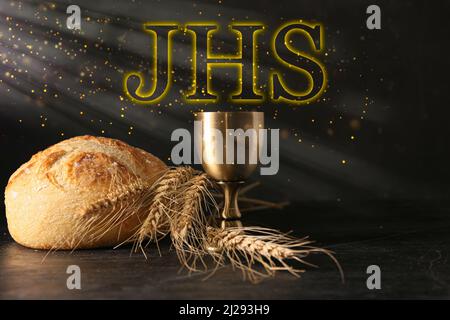 Calice di vino con pane su sfondo scuro. Concetto di comunione Santa Foto Stock