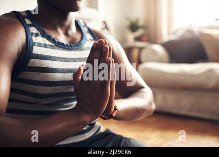La meditazione mi mantiene allineato a me e al mondo. Primo piano di un uomo irriconoscibile che medita a casa. Foto Stock