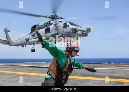 SOUTH CHINA SEA (30 marzo 2022) Aviation Structural Mechanic Airman Keller Curry, di Wasilla, Alaska, segnala un elicottero MH-60R Sea Hawk, assegnato ai 'Raptors' di Helicopter Maritime Strike Squadron (HSM) 71, per il lancio dal ponte di volo della portaerei di classe Nimitz USS Abraham Lincoln (CVN 72). Abraham Lincoln Strike Group è in fase di implementazione pianificata nell'area delle operazioni della flotta USA 7th per migliorare l'interoperabilità attraverso alleanze e partnership, fungendo da forza di risposta pronta a supportare una regione indopacifica libera e aperta. (STATI UNITI Foto Navy di Mass Commu Foto Stock