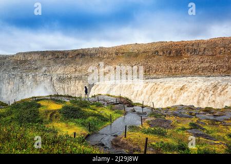 Escursionisti ai margini di Dettioss, turisti ad una gola, cascata con masse d'acqua in caduta, foschia, fiume Joekulsa a Fjoellum, Islanda settentrionale Foto Stock