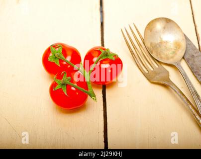 Pomodori maturi ciliegia cluster su bianco rustico tavola di legno Foto Stock