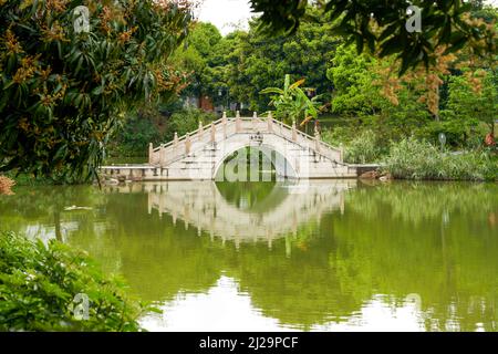 Ponte ad arco in pietra sul lago nel parco cinese Foto Stock