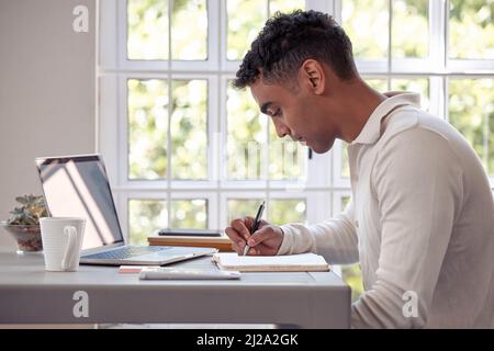 C'è tempo per lavorare. E tempo per l'amore. Scatto di un giovane maschio iscritto nel suo diario a casa. Foto Stock