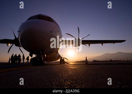 Silhouette di un aeroplano vicino alla pista di un aeroporto che sorica il tramonto serale. Persone che si imbarcarano sull'aeromobile. Foto Stock
