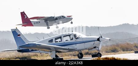 Helgoland, Germania. 25th Mar 2022. Un velivolo privato si riscalda su un grembiule del campo aereo sulla duna di Helgoland, mentre un volo di linea della Ostfriesischer Flug-Dienst (OFD) decollera sullo sfondo. Credit: Markus Scholz/dpa/Alamy Live News Foto Stock