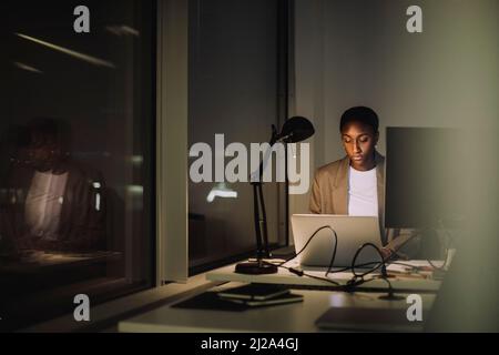 Donna d'affari ambiziosa che usa il laptop mentre lavora all'ultimo minuto in ufficio Foto Stock