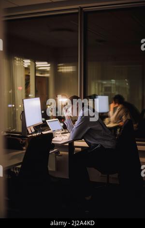 Donna d'affari esausta che lavora fuori orario in ufficio di notte Foto Stock