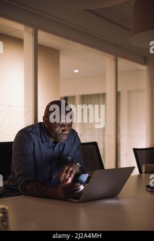 Uomo d'affari maturo che lavora tardi sul laptop in ufficio di notte Foto Stock