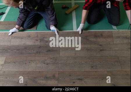 Un lavoratore bussa a mano su un laminato che collega i pannelli con un clic di blocco Foto Stock